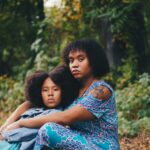 woman sitting in front of child sitting beside trees